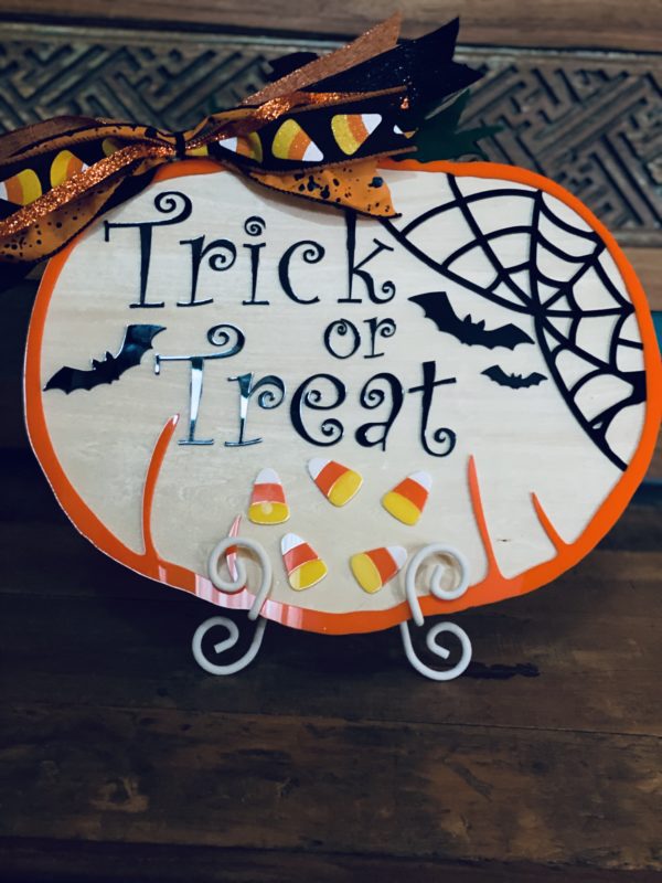 Trick or treat plaque with black spider webs and candy corn.