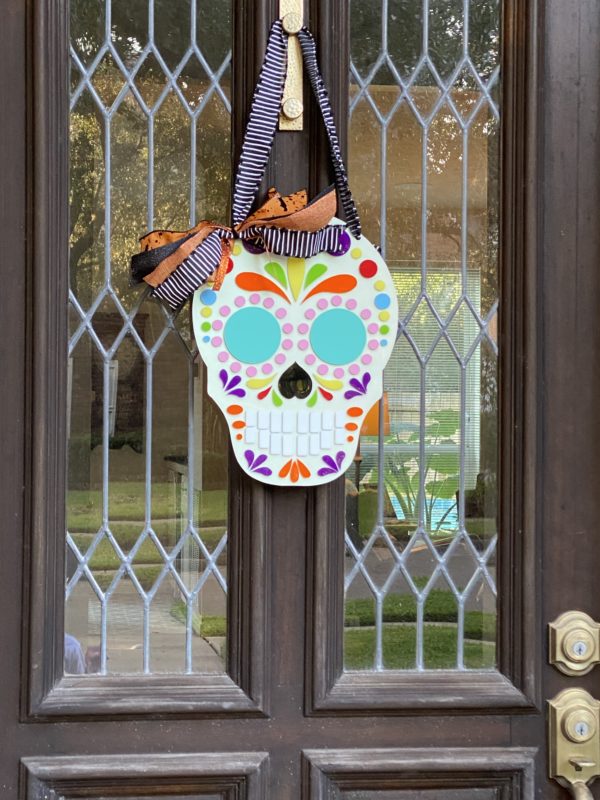 Sugar Skull with blue eyes hanging on a door.